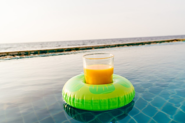 Orangensaftglas mit Schwimmring am Außenpool