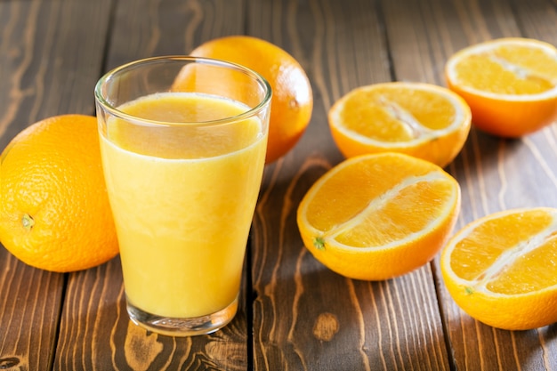 Orangensaftglas und Früchte auf Holztisch.