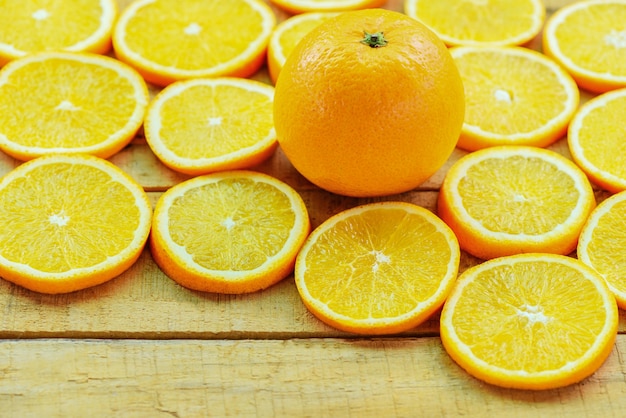Orangenscheibe auf hölzernem Hintergrund und frischen Orangenfrüchten, gesunde Früchte