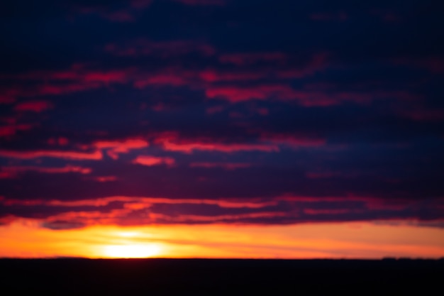 Orangepurple borrosa dramáticas nubes iluminadas por el sol poniente contra el cielo vespertino