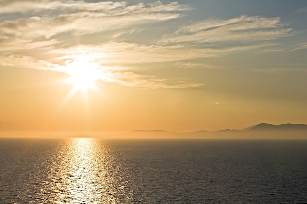 Oranger Sonnenaufgang über Hügeln und Meer