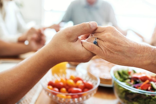 Orar tomados de la mano y la comida de la familia en la mesa del comedor con fe, gratitud y estilo de vida cristiano. Orar juntos, confianza y personas espirituales con almuerzo saludable o comida festiva