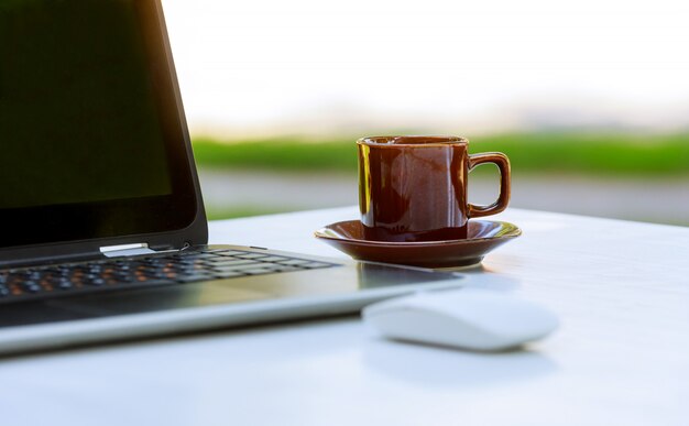 Ordenador portátil del cuaderno con café caliente en la tabla de madera.