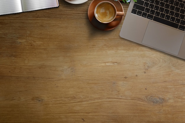 Ordenador portátil con el espacio marrón de la taza y de la copia de café en la tabla de madera del escritorio.