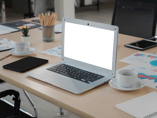 Ordenador portátil con pantalla en blanco en blanco y tableta en la mesa de trabajo de madera en la oficina
