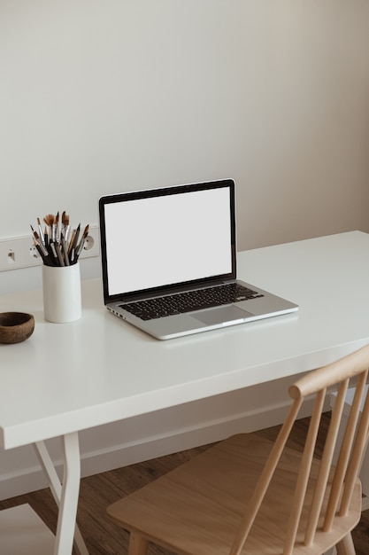 Ordenador portátil de pantalla en blanco. Espacio de trabajo de la mesa del escritorio de la oficina en casa