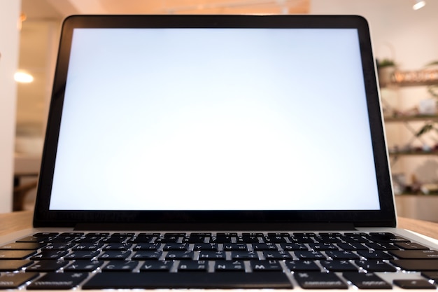 Ordenador portátil con pantalla en blanco en la mesa de la cafetería desenfoque de fondo con bokeh. Teclado, uso en el sistema operativo del alfabeto chino tradicional.