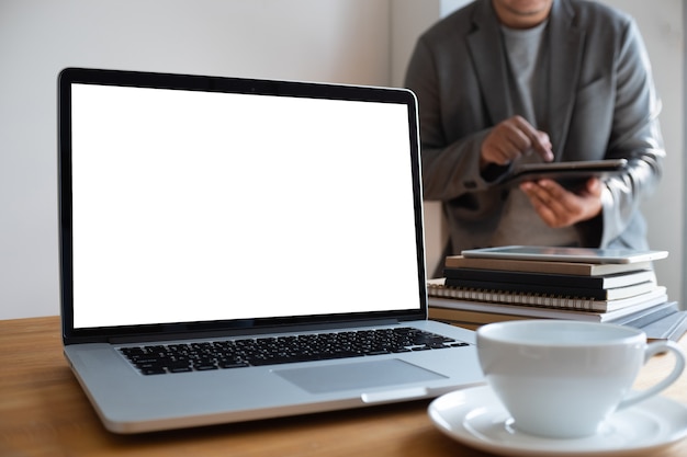 Ordenador portátil con pantalla en blanco en la mesa. Nuevo proyecto de fondo de área de trabajo en la computadora portátil con co en blanco