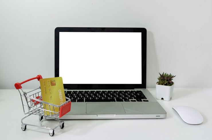 Foto ordenador portátil simulacro de blanco en blanco y carro y tarjeta de crédito en el escritorio. se utiliza para poner texto o información para anunciar noticias o vender productos en línea. concepto de negocio de marketing