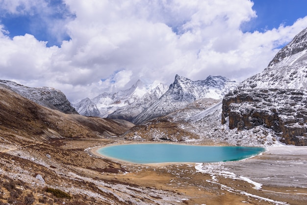 Ordeñe el lago en las montañas de la nieve con las nubes y el cielo en Yading, China.