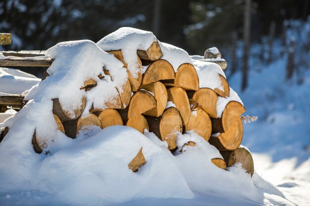 Ordentlich angehäufter stapel gehacktes trockenes stammholz draußen bedeckt mit schnee am sonnigen tag des hellen kalten winters, abstrakt