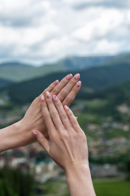 Ordentliche Maniküre auf kurzen Nägeln Weibliche Hände auf dem Hintergrund der Berge Vertikaler Rahmen