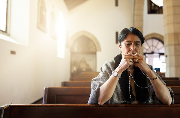 Ore a igreja e a senhora idosa rezando com um rosário em uma calma capela zen sozinha, sagrada e espiritual Adoração de oração e senhora mexicana se conectam com Deus Jesus e a religião cristã no México