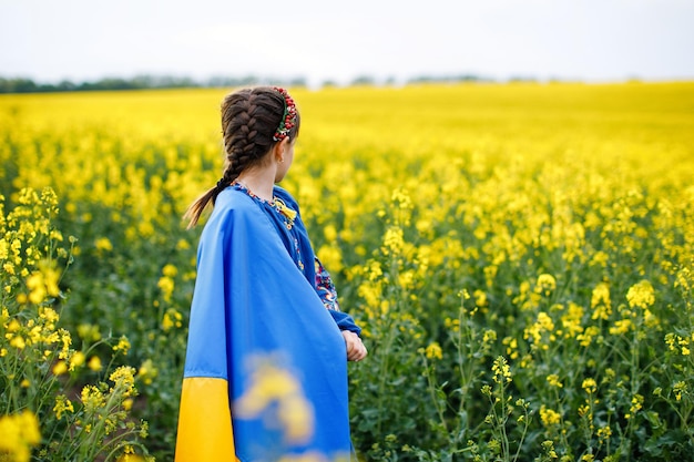 Ore pela Ucrânia Criança com bandeira ucraniana no campo de colza Menina segurando a bandeira nacional na mão Criança feliz comemorando o Dia da Independência