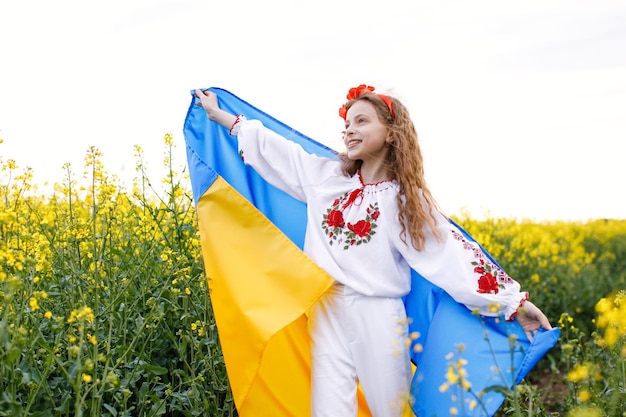 Ore pela Ucrânia Criança com bandeira ucraniana no campo de colza Menina segurando a bandeira nacional rezando pela paz Criança feliz comemorando o Dia da Independência