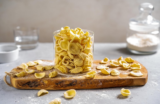 Foto orecchiette são massas italianas típicas de puglia em frasco de vidro na tábua com ingredientes principais