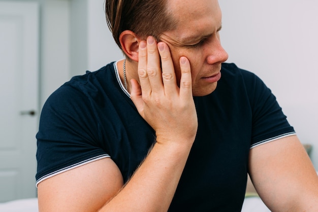 La oreja del hombre está inflada y sufre de dolor.