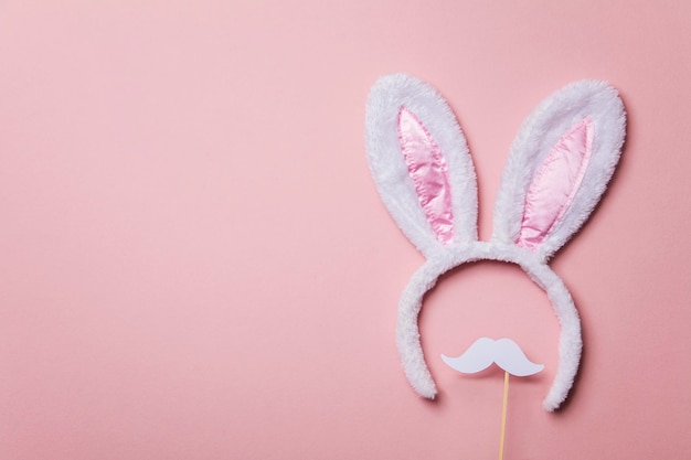 Orejas de conejo de pascua con bigote blanco sobre un fondo rosa pastel