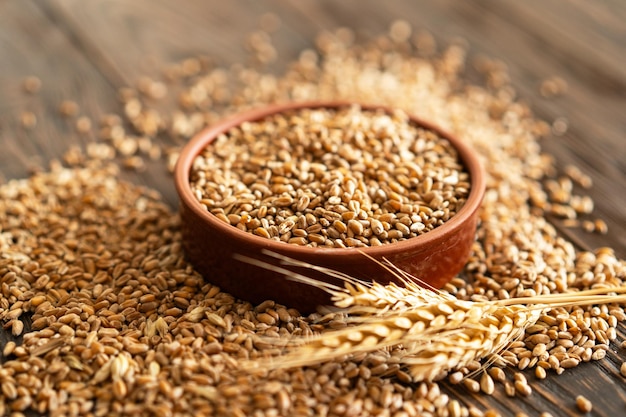 Orejas de trigo y cuenco de granos de trigo sobre un fondo de madera