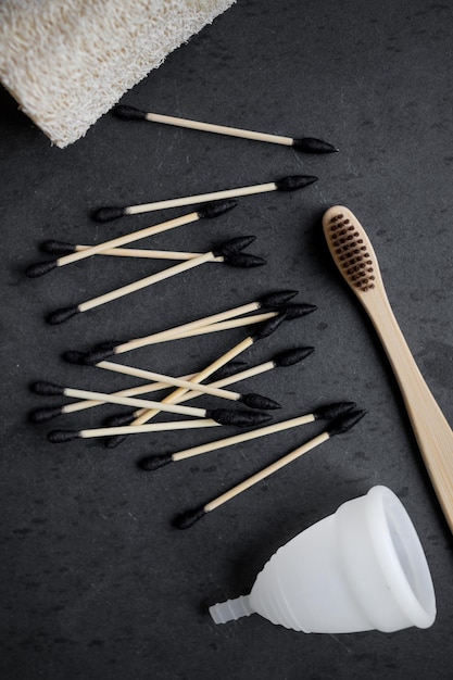 Foto orejeras biodegradables cepillos de dientes y copa menstrual sobre un fondo liso