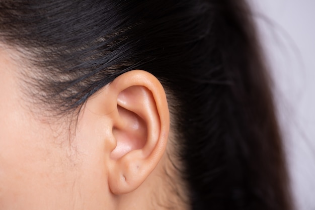 Orelha jovem mulher asiática com piercing na orelha.