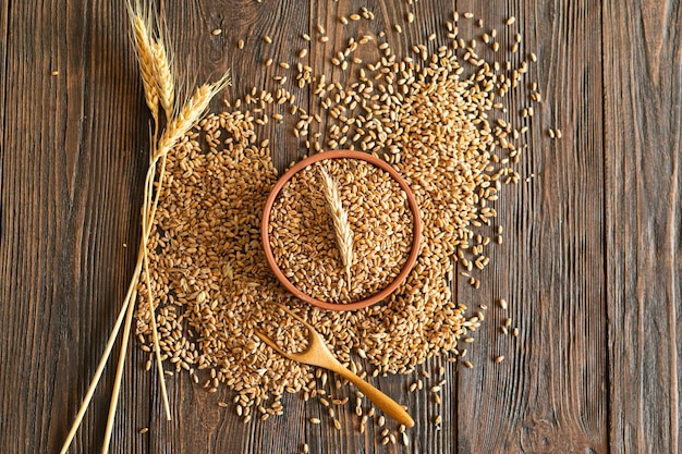 Orelhas de trigo e uma tigela de grãos de trigo em fundo de madeira