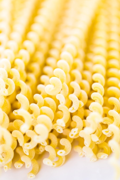 Organische gelbe lange Pasta-Spiralen auf weißem Hintergrund.