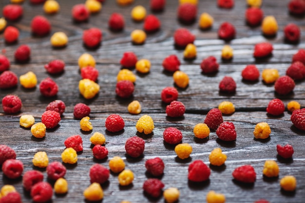 Organische gelbe und rote Himbeeren gemischt auf hölzernem Hintergrund.