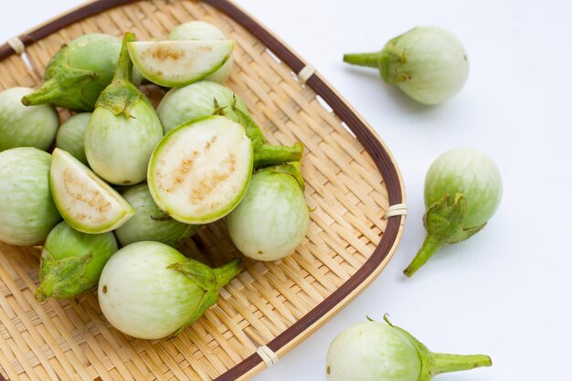 Organische grüne Aubergine im Bambuskorb auf weißem Hintergrund.