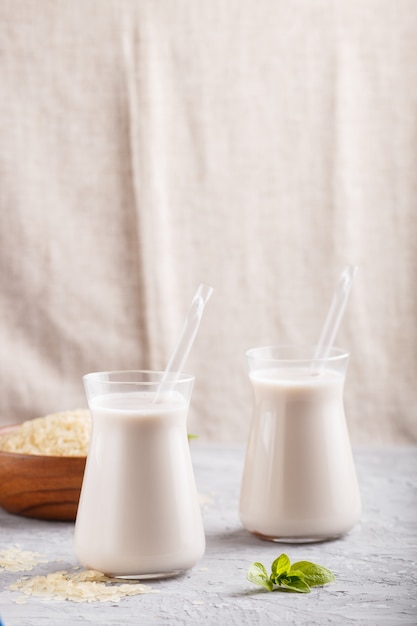 Organische Nichtmilchreismilch in der Glas- und Holzplatte mit Reissamen