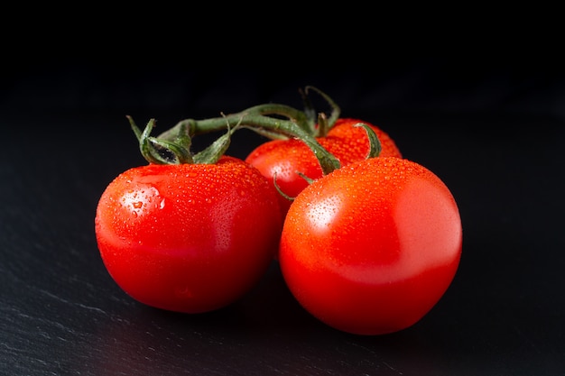 organische Tomaten auf schwarzem Schieferbrett mit Kopienraum