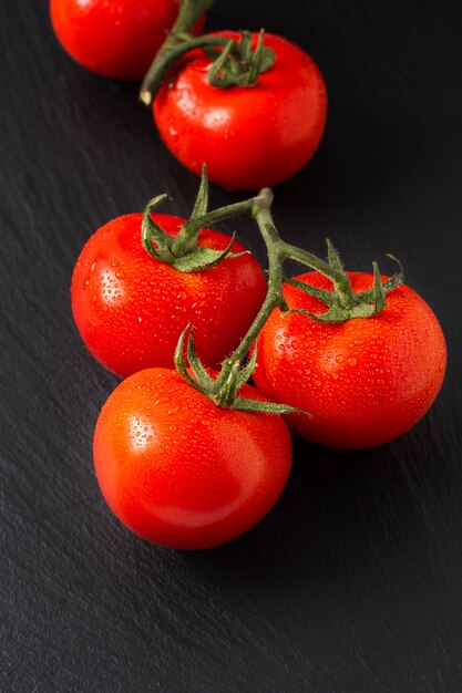 Organische Tomaten des Lebensmittelkonzeptes auf schwarzem Schieferbrett mit Kopienraum