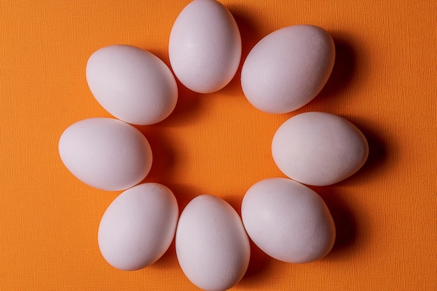 Organische weiße eier in einem rohen auf orange pastell backgound.