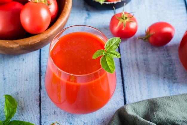 Foto organischer hausgemachter tomatensaft mit basilikumblättern in einem glas auf dem tisch