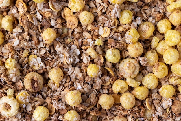 Organisches hausgemachtes geröstetes knuspriges Müsli mit Haferflocken und Leinsamenflocken und knusprigen Maisbällchen und -ringen Draufsicht flach gelegte Müsli-Hintergrundtextur