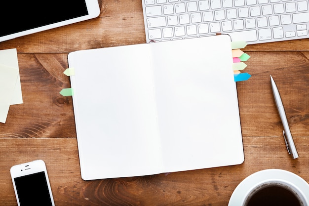 Foto organizador de cuaderno abierto en la mesa de la computadora con dispositivos de escritorio de café