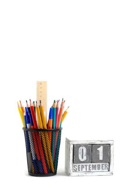 Organizador con lápices y regla, soporte de papelería y calendario de madera con fecha 01 de septiembre, fondo blanco