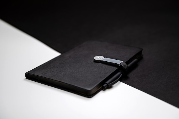 Organizador negro o cuaderno con bolígrafo en espacio de copia de maqueta de fondo blanco y negro de dos colores