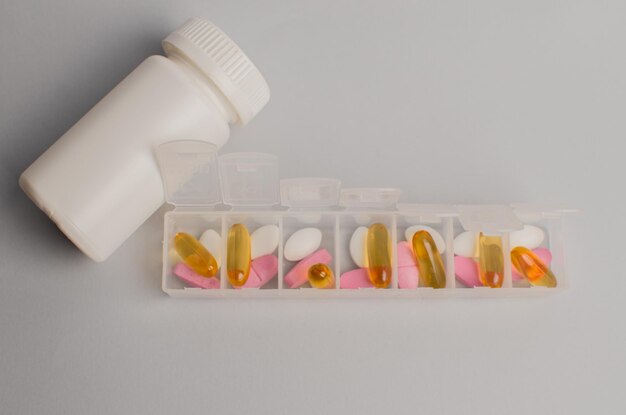 Foto organizador para pílulas vitaminas suplementos dietéticos em um fundo cinza conceito de manutenção da saúde