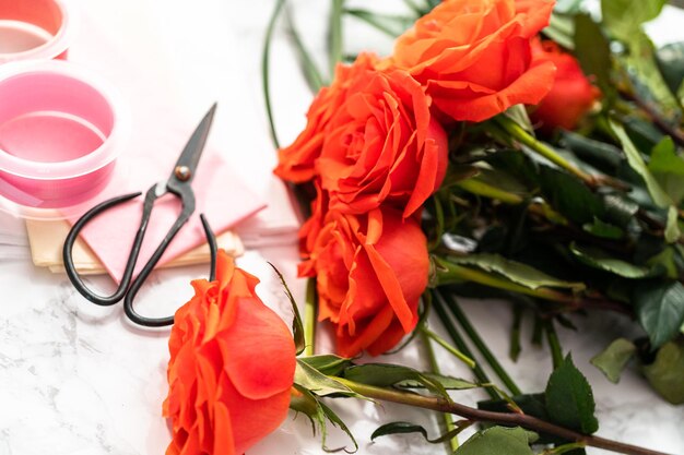 Organizando rosas vermelhas e folhas verdes em um buquê em um fundo de mármore.