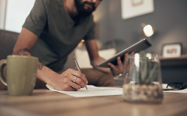 Organizando su acto financiero Captura recortada de un hombre que usa una tableta digital mientras realiza el papeleo en casa