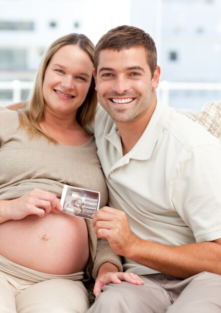 Orgulhoso futuro mãe e pai mostrando uma ecografia para a câmera