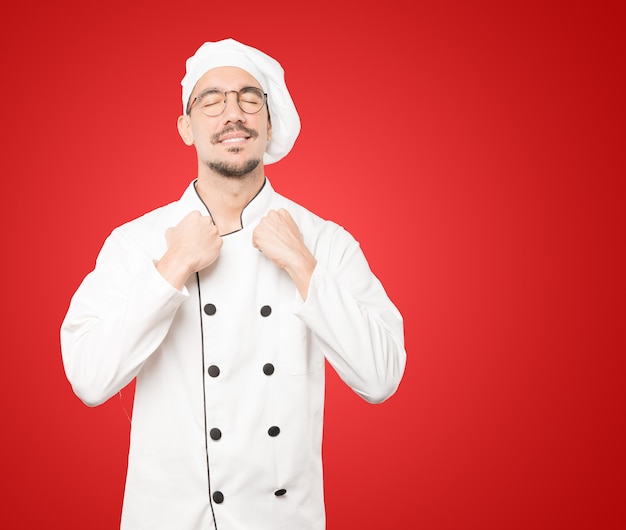 Foto orgulhoso jovem chef fazendo um gesto de força com o braço