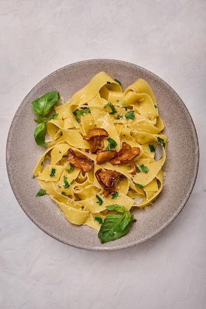 Orientación vertical pappardelle de pasta con champiñones rebozuelos queso y perejil en la parte superior de la placa