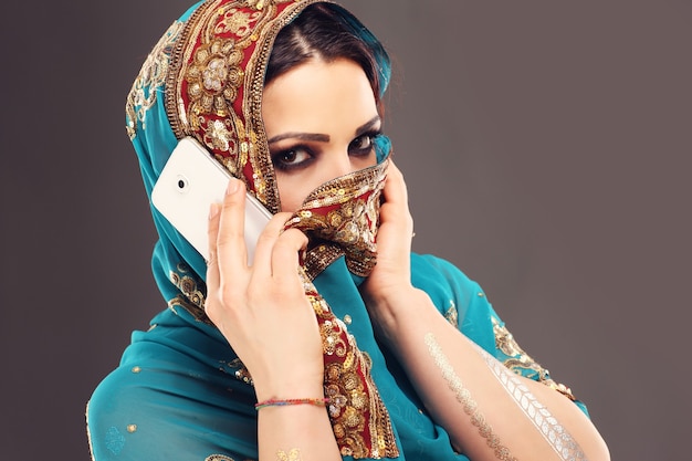 orientalische Frau, die auf Smartphone spricht