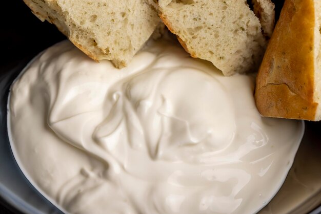 Orientalisches Fladenbrot aus Weizenmehl mit Sauerrahm, Teilen orientalischen frischen Fladenbrots auf dem Tisch und Sauerrahm aus Milch