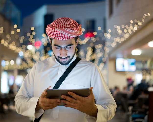 Oriente médio jovem com tablet na cidade à noite