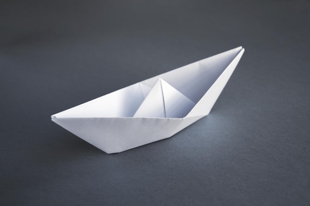 Origami de barco de papel blanco aislado en un fondo gris