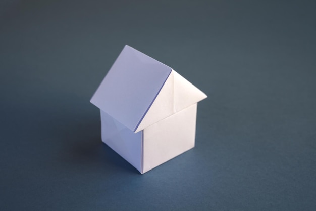 Origami de casa de papel blanco aislado en un fondo gris en blanco.