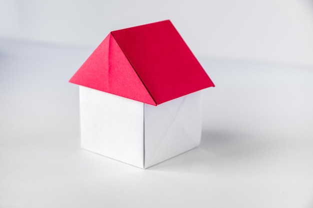 Origami de casa de papel blanco y rojo aislado sobre fondo blanco